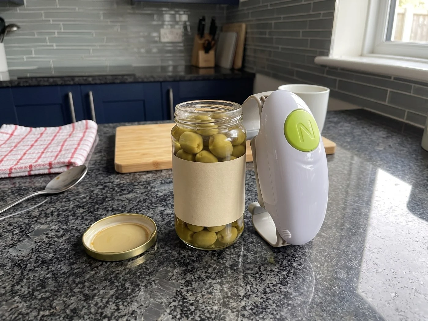 Opened olive jar with Twist Buddy Pro resting beside it